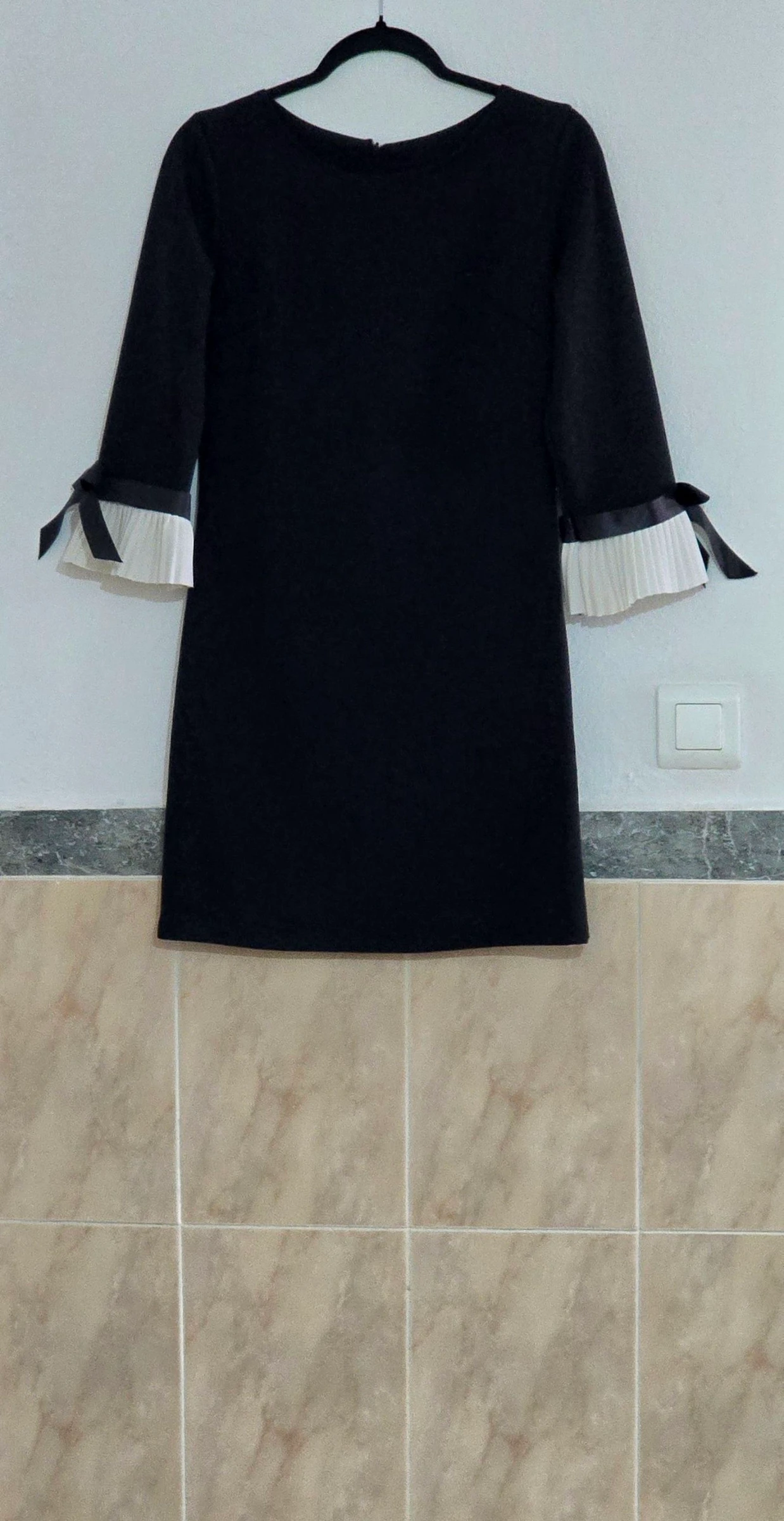 Vestido negro con puños plisados en contraste.